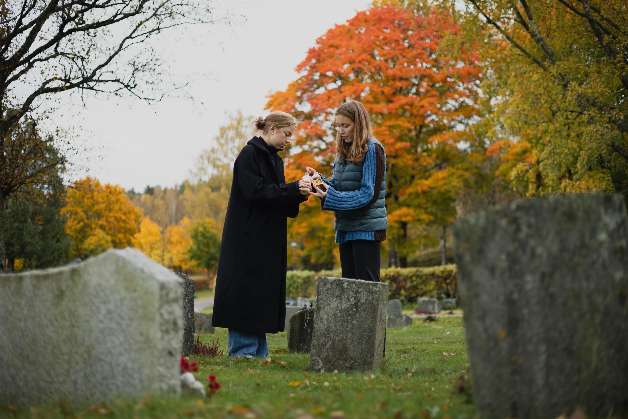 To damer som tenner lys på kirkegård